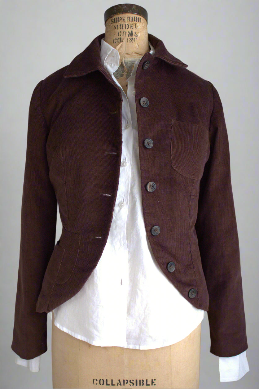 Brown jacket on a mannequin with a white shirt underneath against a plain background