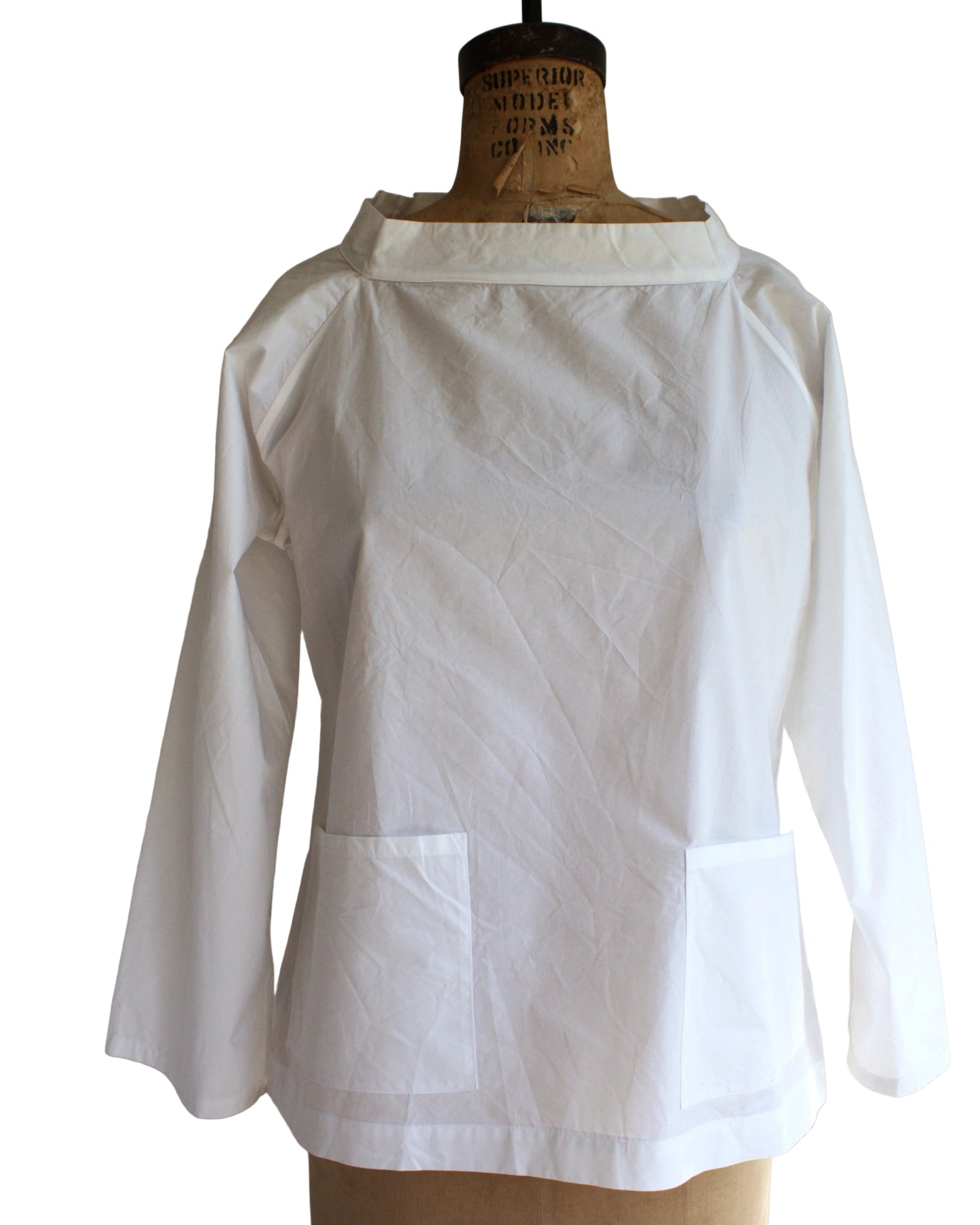 White shirt on a mannequin against a white paneled wall